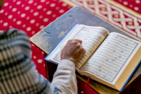 Téléchargez les photos : Vue arrière d'un musulman solitaire récitant le Saint Coran dans une mosquée pour guérir son âme pendant le Ramadan - en image libre de droit