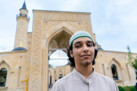 Foto de Retrato de un joven de apariencia musulmana saliendo de la mezquita después de la oración en una terraza con ornamentos islámicos - Imagen libre de derechos