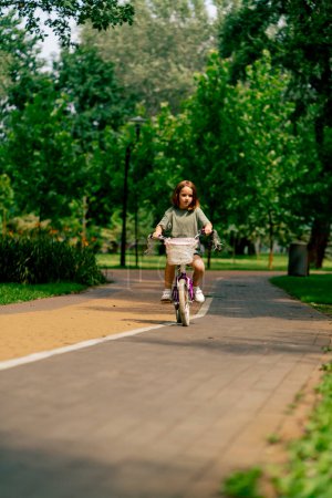 Photo for Portrait of a little girl riding bicycle in the park child without adult supervision childhood - Royalty Free Image