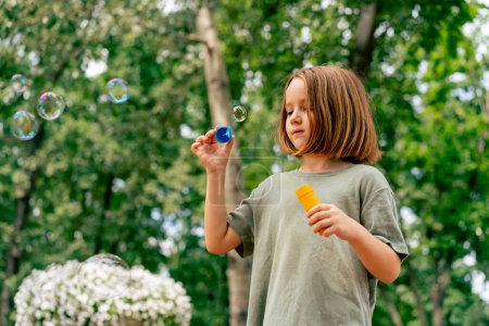 Foto de Retrato hermosa linda niña soplando burbuja de jabón en el parque de la ciudad feliz infancia despreocupada - Imagen libre de derechos