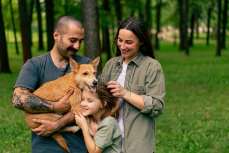 Photo for Portrait of happy young family in park with dog dad mom daughter resting concept trust care and family values - Royalty Free Image