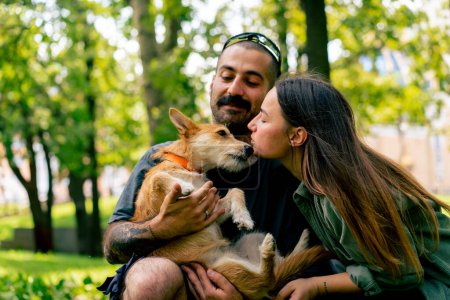 Foto de Retrato de una joven pareja enamorada caminando en el parque con su mascota besándolo amor perros cuidado romance - Imagen libre de derechos
