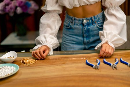 Téléchargez les photos : Gros plan des mains d'une femme mesurant la longueur d'une chaîne en or pour créer un beau bracelet - en image libre de droit