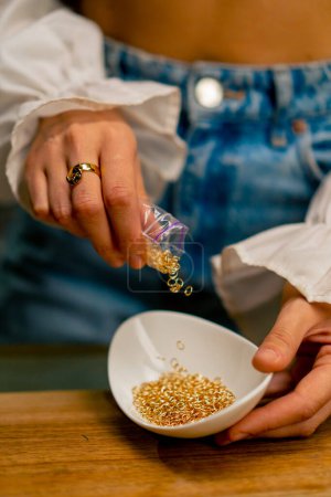 Foto de Primer plano manos femeninas derramando hermosas cuentas para un collar o pendientes de la producción de joyas artesanales de belleza - Imagen libre de derechos