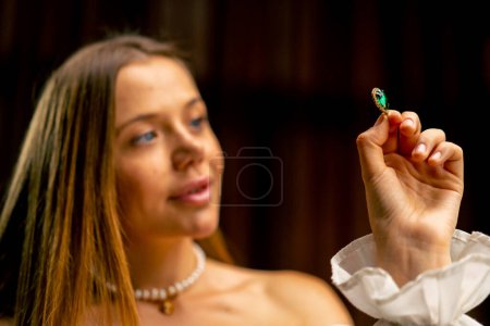 Foto de Primer plano una joven hermosa niña examina cuidadosamente las cuentas de un collar o pendientes antes de comenzar la producción de joyas artesanales - Imagen libre de derechos
