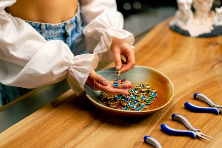 Foto de Manos femeninas sosteniendo piedras multicolores y colgantes para la joyería artesanal collar haciendo la belleza del hogar de cerca - Imagen libre de derechos