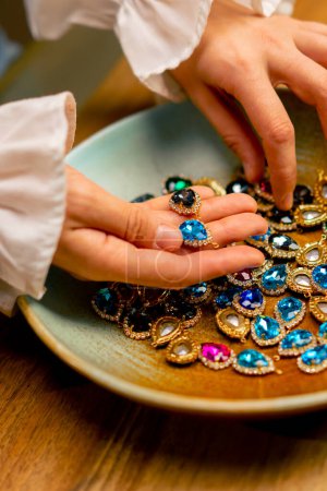 Foto de Manos femeninas sosteniendo piedras multicolores y colgantes para la joyería artesanal collar haciendo la belleza del hogar de cerca - Imagen libre de derechos