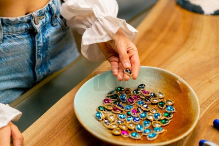 Téléchargez les photos : Mains féminines tenant des pierres multicolores et des pendentifs pour collier artisanat bijoux faisant maison beauté close-up - en image libre de droit