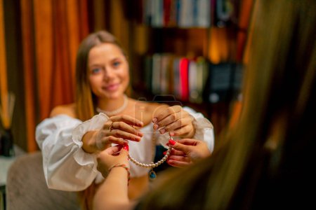 Photo for Beautiful young needlewoman gives a custom-made pearl necklace to a customer jewelry crafting hobby work home - Royalty Free Image