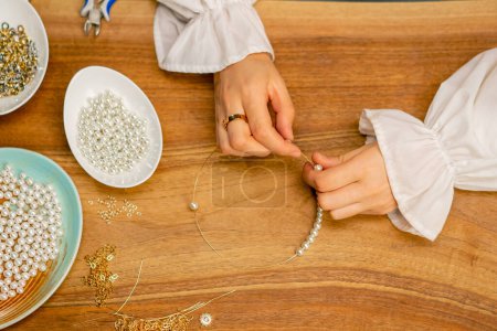 Téléchargez les photos : Mains en gros plan d'une jeune fille fait des bijoux avec ses propres mains cordes perles sur un fil pour collier passe-temps - en image libre de droit