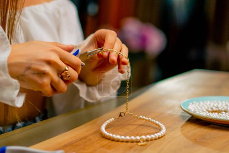 Photo for Close-up a young beautiful girl makes jewelry with her own hands cuts the remnants of wire for necklace with pliers craft production - Royalty Free Image