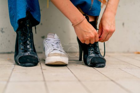 Foto de Primer plano de las piernas de bailarina en zapatos negros de tacón alto chica atando cordones de zapatos en la sexualidad callejera - Imagen libre de derechos