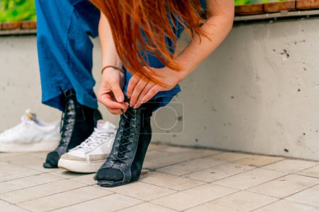 Photo for Close-up of dancer's legs in black high-heeled shoes girl tying shoelaces on street sexuality - Royalty Free Image