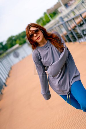 Photo for Young red-haired street hip-hop dancer in sportswear dances impromptu dance us bridge attract the attention passers-by hobbies active lifestyle - Royalty Free Image