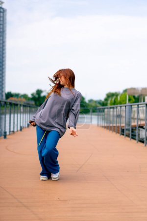 Téléchargez les photos : Jeune rousse hip-hop danseur de rue dans les danses de vêtements de sport danse impromptue nous pont attirer l'attention passants passe-temps mode de vie actif - en image libre de droit