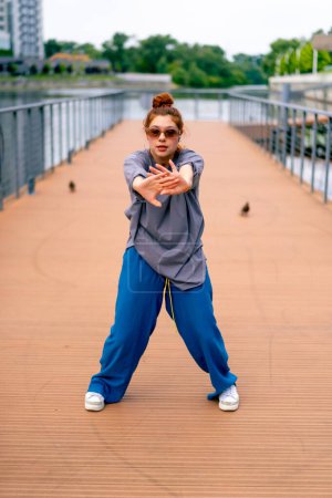 Foto de Joven pelirroja calle hip-hop bailarina en ropa deportiva bailes improvisada danza nosotros puente atraer la atención transeúntes aficiones estilo de vida activo - Imagen libre de derechos