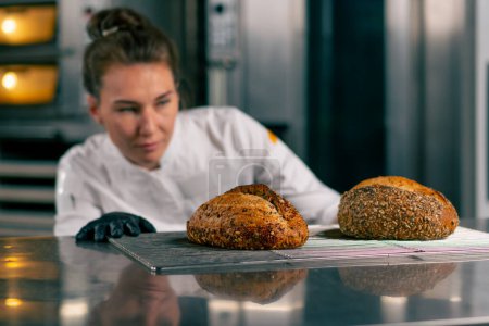Téléchargez les photos : Gros plan de pains fraîchement cuits qu'une fille souriante fait cuire sur une grille à pâtisserie - en image libre de droit