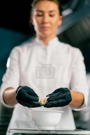 Photo for Close-up shot of female hands in gloves breaking yeast to prepare dough for baking bread in a bakery - Royalty Free Image