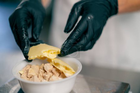 Téléchargez les photos : Gros plan des mains féminines dans des gants avec du beurre pour préparer la pâte à pain dans une boulangerie - en image libre de droit