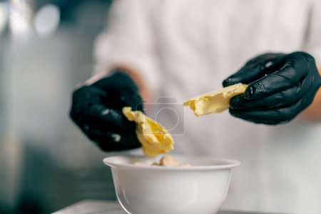 Foto de Primer plano de las manos femeninas en guantes con mantequilla para preparar masa para hornear pan en una panadería - Imagen libre de derechos