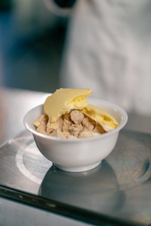 Foto de Primer plano de los trozos preparados de levadura y mantequilla que se encuentran en un tazón en una escala de cocina para hacer masa - Imagen libre de derechos