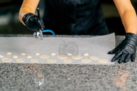 Photo for The female hand of a confectioner in a glove uses a special device to dry chocolate candies on parchment - Royalty Free Image