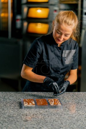 Photo for A woman professional chocolatier mixes different types of chocolate to prepare natural chocolate - Royalty Free Image
