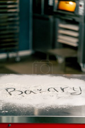 Téléchargez les photos : Inscription créative en grandes lettres avec farine sur la surface de la cuisine sur la table Boulangerie - en image libre de droit