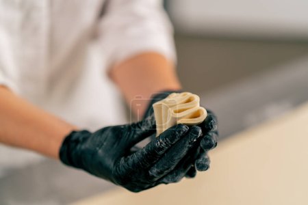 Téléchargez les photos : Gros plan sur les mains d'une cuisinière pétrissant soigneusement la pâte pour préparer et cuire le pain dans une boulangerie - en image libre de droit