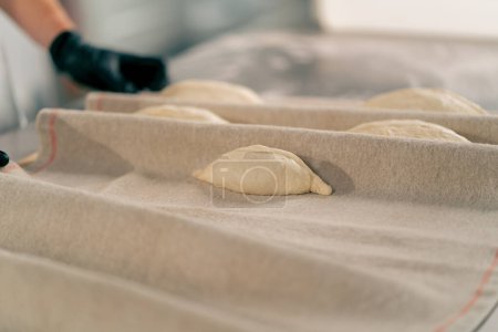 Téléchargez les photos : Gros plan sur les mains d'une cuisinière pétrissant soigneusement la pâte pour préparer et cuire le pain dans une boulangerie - en image libre de droit
