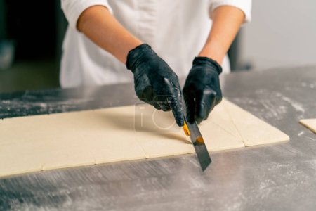 Photo for Close-up shot of a female chef's hands carefully kneading dough for preparing and baking bread in a bakery - Royalty Free Image