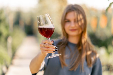 Foto de Retrato de una hermosa chica de pelo largo toma un sorbo de vino de una copa y lo entrega a la cámara con una sonrisa - Imagen libre de derechos