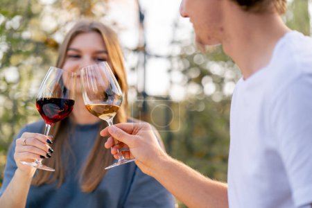 Photo for Close-up shot of a girl clinking glasses with different types of wine with a guy sitting together on the terrace - Royalty Free Image