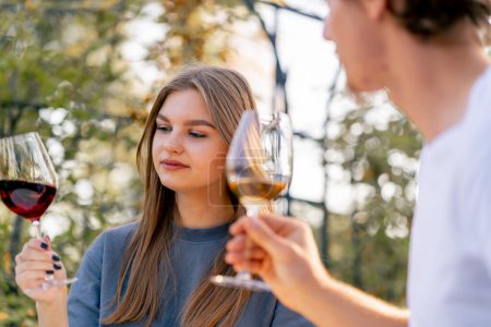 Photo for Close-up shot of a girl clinking glasses with different types of wine with a guy sitting together on the terrace - Royalty Free Image