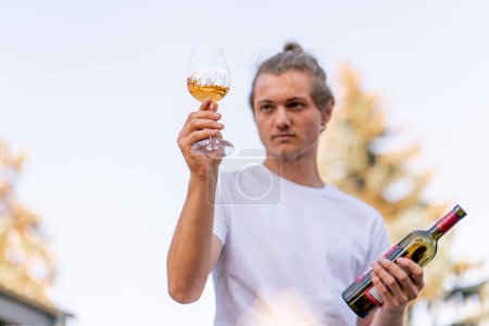 Foto de Sommelier profesional masculino prepara una botella de vino para degustar a los huéspedes en el jardín de la bodega - Imagen libre de derechos