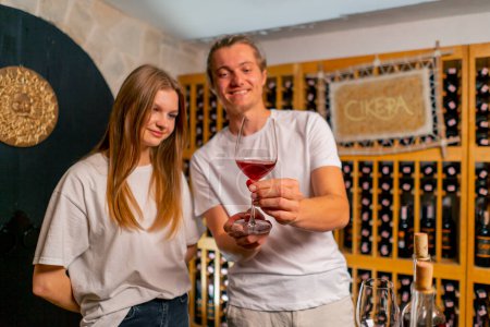 Téléchargez les photos : Deux jeunes hommes et femmes dégustant différents types de vin ensemble dans une cave souterraine dans une cave - en image libre de droit