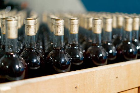 Téléchargez les photos : Gros plan des bouteilles de vin vieilli avec bouchons en bois dans des boîtes stockées dans une cave d'une cave - en image libre de droit
