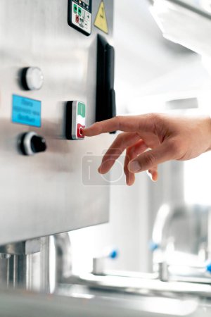 Foto de Primer plano de la mano de un hombre presionando el botón de encendido y apagado en una máquina de fermentación con su dedo - Imagen libre de derechos