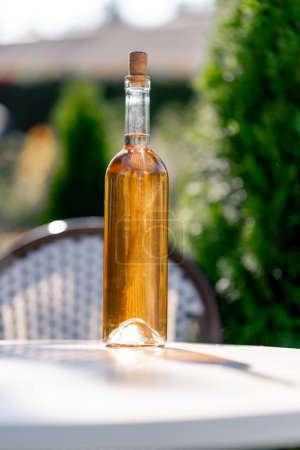 Photo for Close-up shot of a glass transparent bottle with wine stands on the table of the summer terrace of a restaurant for tasting - Royalty Free Image