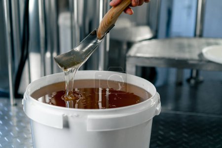 Téléchargez les photos : Gros plan d'une cuillère en métal remuant du miel liquide naturel qui retourne dans un grand bol - en image libre de droit