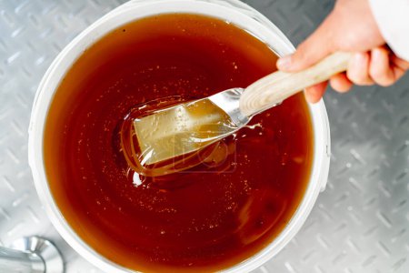 Téléchargez les photos : Plan supérieur d'une cuillère métallique spéciale mélangeant du miel liquide naturel qui se déverse dans un grand bol - en image libre de droit