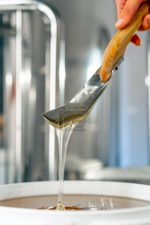 Photo for Close-up shot of a metal spoon stirring natural liquid honey which flows back into a large bowl - Royalty Free Image