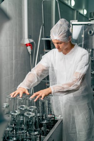 Téléchargez les photos : Un employé d'une usine de production de boissons alcoolisées prépare des bouteilles en verre vides à remplir de vin pour un stockage ultérieur - en image libre de droit