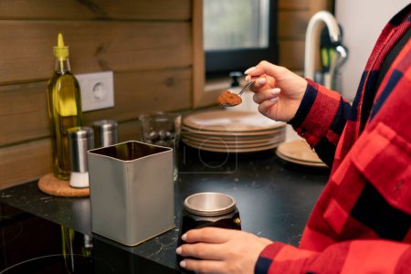 Foto de Una joven prepara café temprano en la mañana en una turbina de géiseres en la cocina de su casa - Imagen libre de derechos