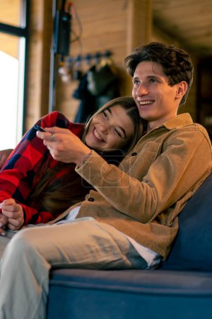 Foto de Una joven pareja romántica relajándose juntos en casa en la sala de estar abrazándose y viendo comedia romántica en la televisión - Imagen libre de derechos