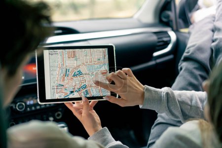 Foto de Una pareja en un coche confiriendo y planeando la mejor ruta a través del bosque usando un mapa en la tableta - Imagen libre de derechos
