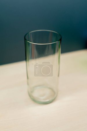 Foto de Un vidrio de vidrio transparente de color se encuentra vacío en una mesa de madera en una tienda de decoración hecha a mano - Imagen libre de derechos