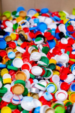 Foto de Primer plano de tapas multicolores de botellas usadas almacenadas en una estación de clasificación de reciclaje y eliminación de residuos - Imagen libre de derechos