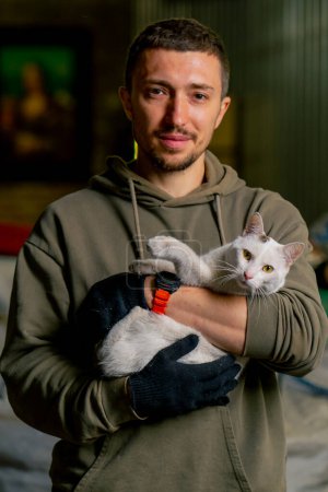 Photo for Portrait of a worker at a waste recycling station holding a local beautiful cat in his arms and smiling - Royalty Free Image