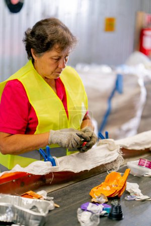 Foto de Una mujer mayor seria trabaja en una estación de reciclaje de residuos y clasifica la basura para su posterior procesamiento - Imagen libre de derechos